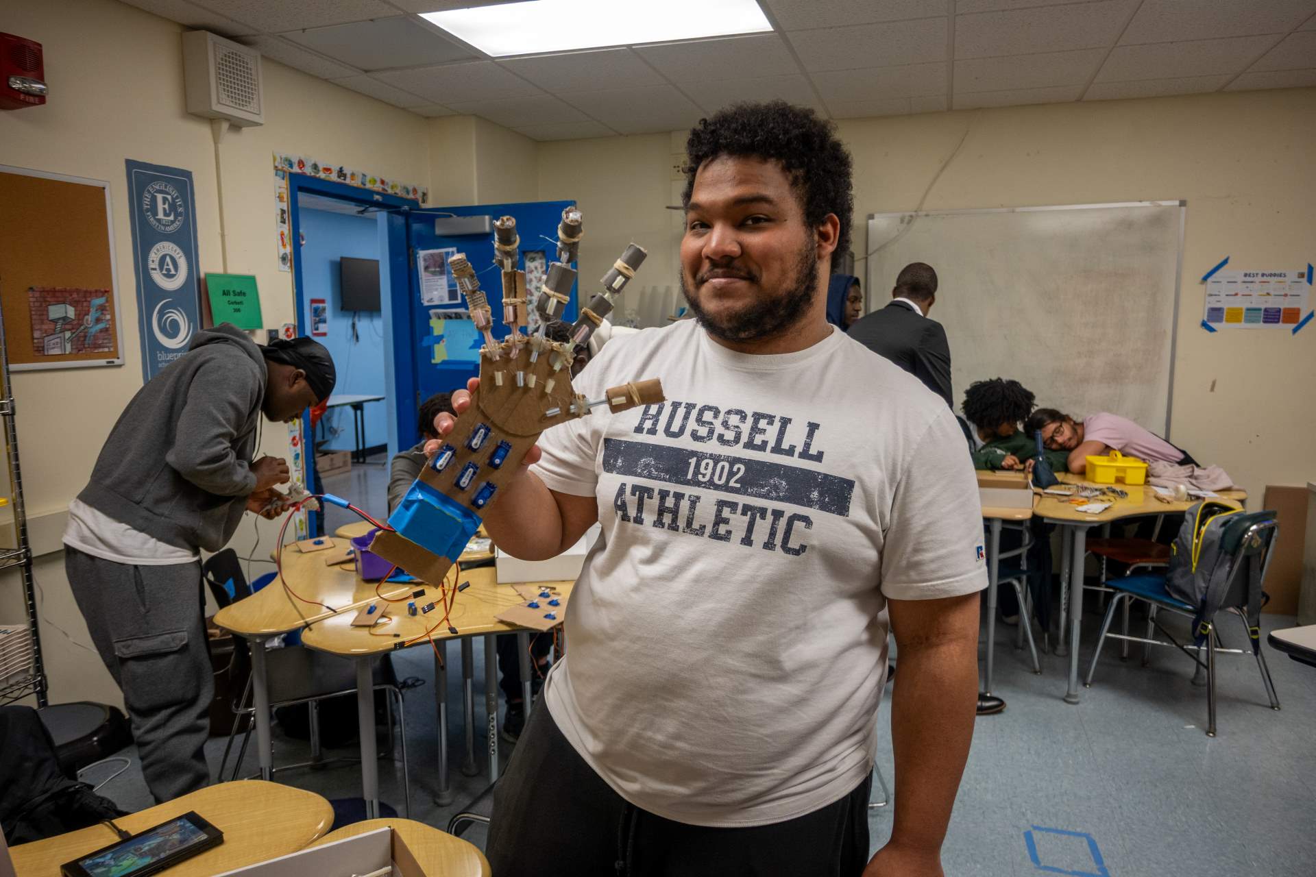 A Boy Holds a Robotic Hand in a School Setting
