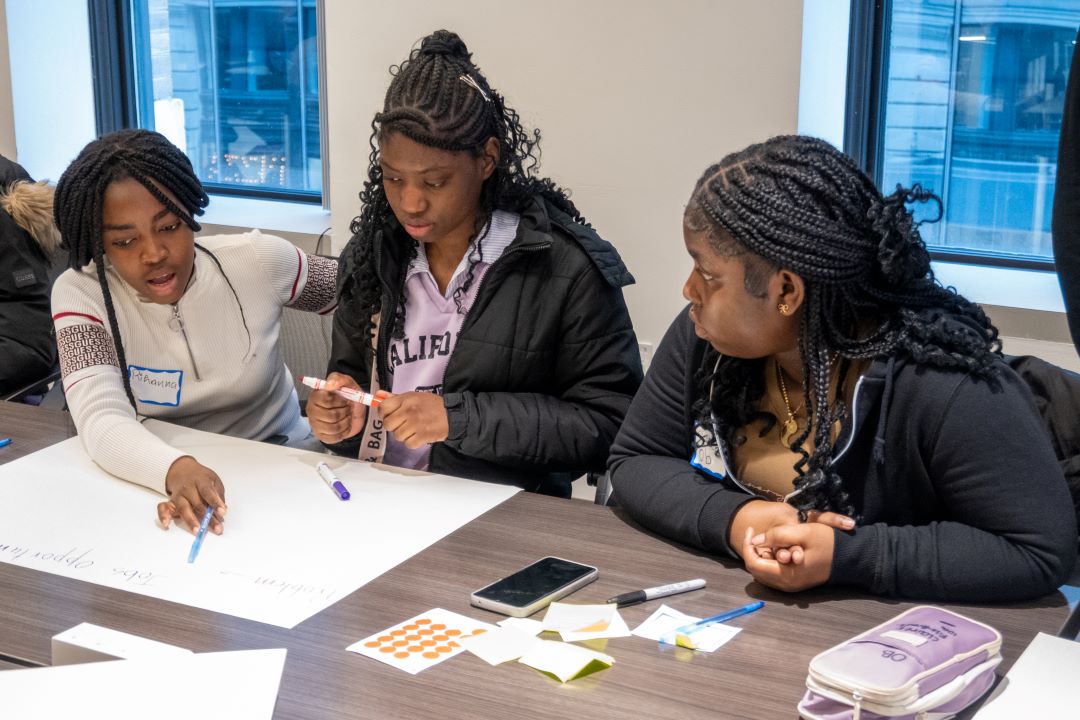 Three students work on a poster board.