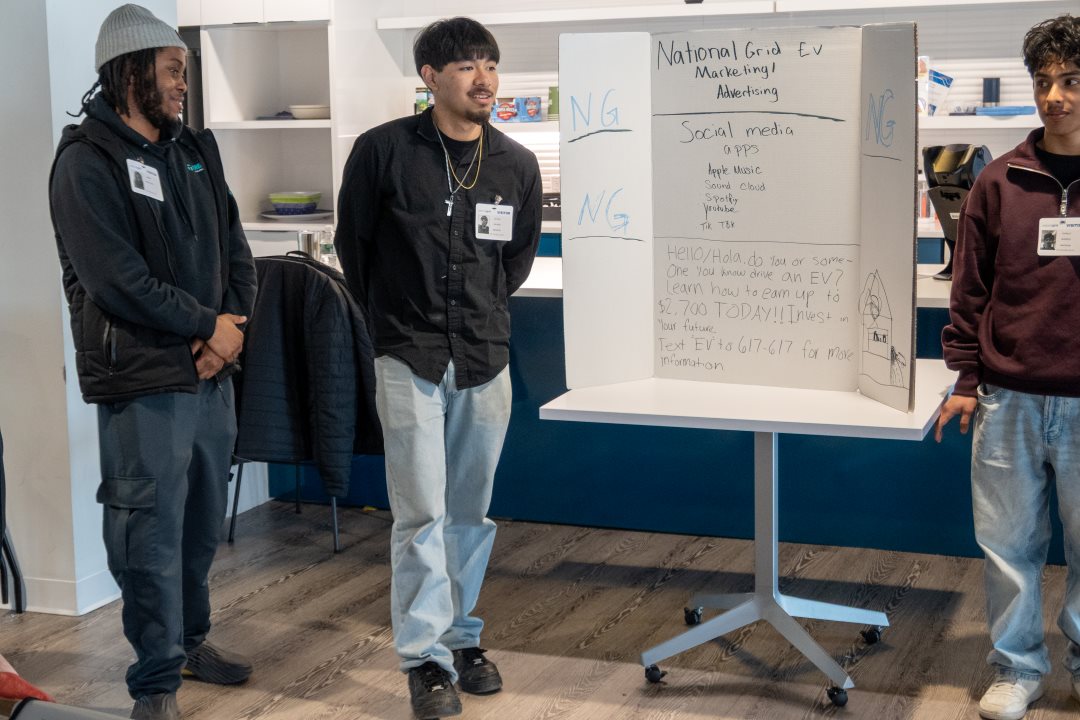 three students present a poster board